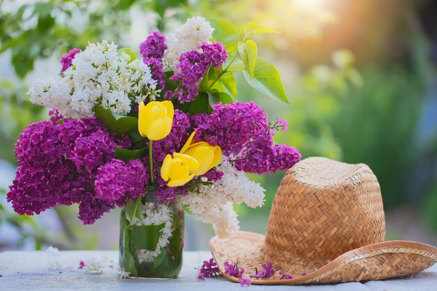 Spring or summer background A bouquet of lilacs and straw panama lit by sunlight