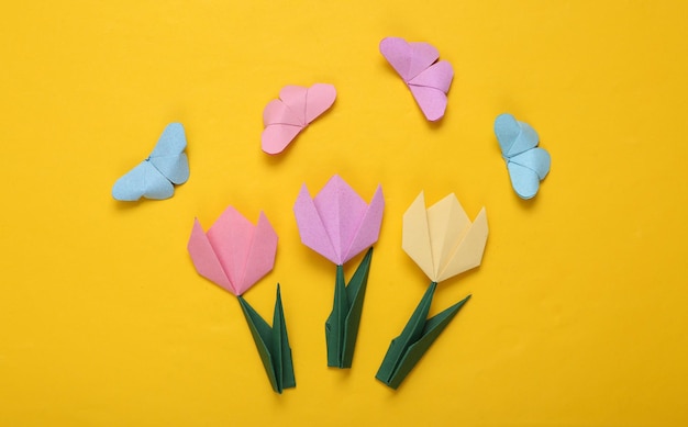 Spring or summer composition of origami tulips and butterflies on yellow background