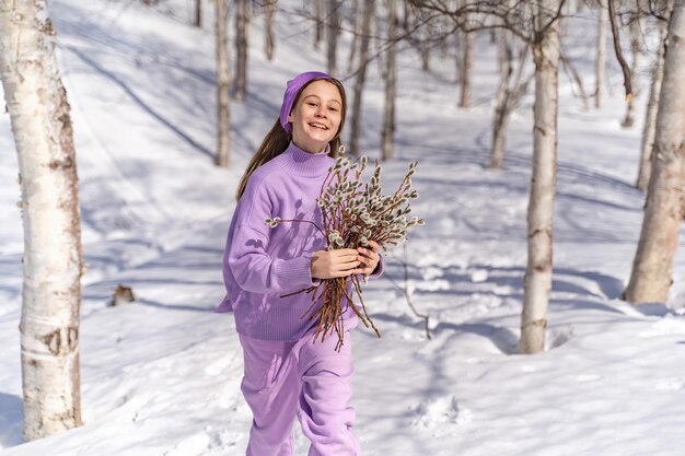 Photo on a spring sunny day a young girl walks travels in the forest collects willow for the easter holida