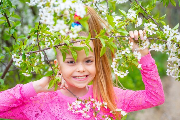 Spring teenager girl over nature green background. Beautiful teenager girl enjoying life in spring blossoming garden. Funny little girl in a blooming garden.