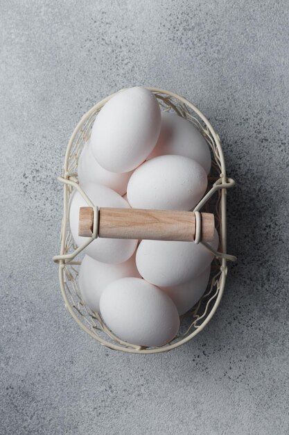 Весенние пасхальные праздники белые яйца в корзине на сером столе