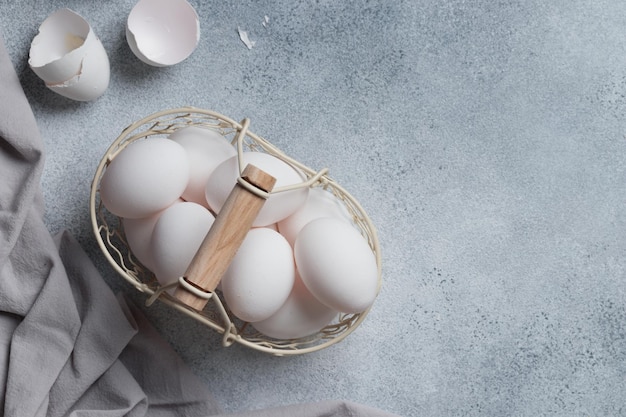 Весенние пасхальные праздники белые яйца в корзине на сером столе