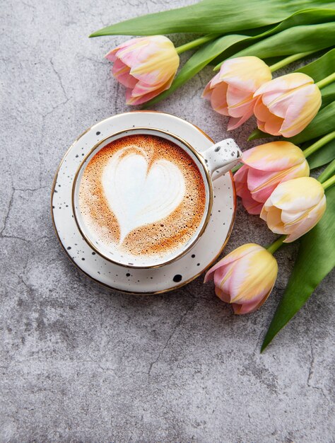 Spring tulips and cup of coffee on a concrete desk