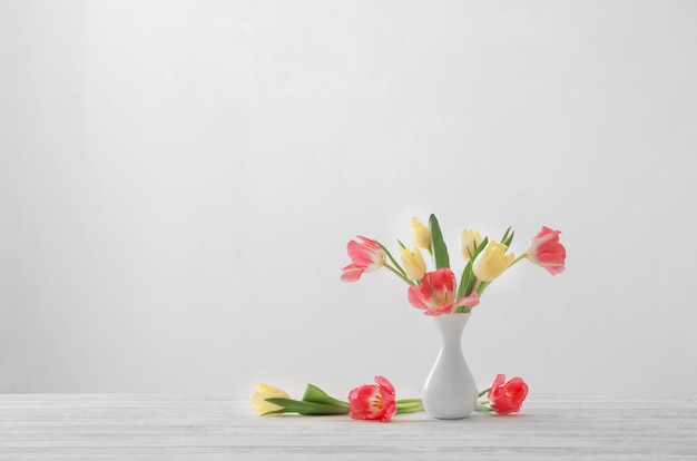 Spring tulips in white vase on white background