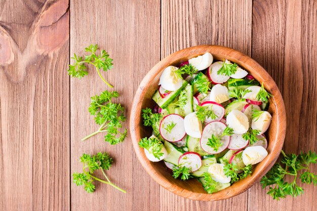Фото Салат из весенних овощей в деревянной тарелке