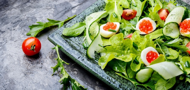 Spring vegetable salad with greens, cucumber, egg and red caviar.Summer food