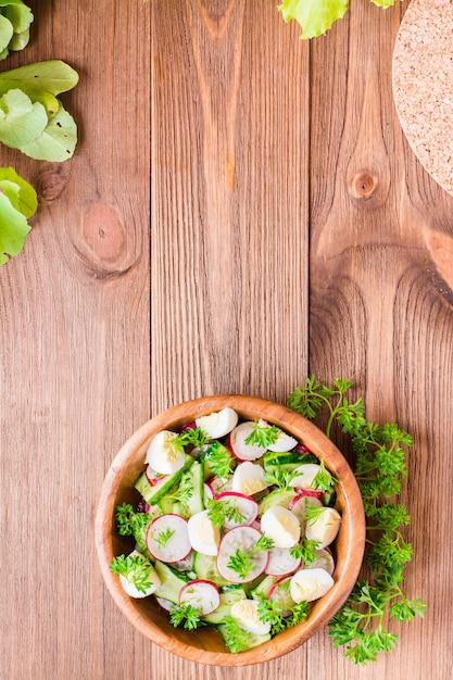 Spring vegetable salad in a wooden plate