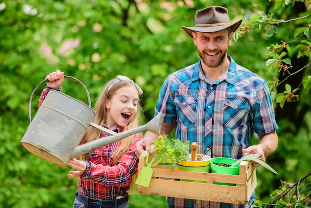 spring village country. little girl and happy man dad. earth day. ecology. watering can and shovel. family farm. father and daughter on ranch. working with flowers.