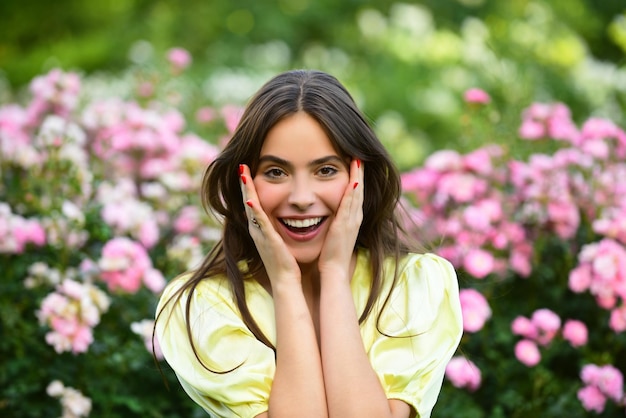 Spring woman smiling in rose garden outdoors. Natural beauty girl enjoy summer recreation.