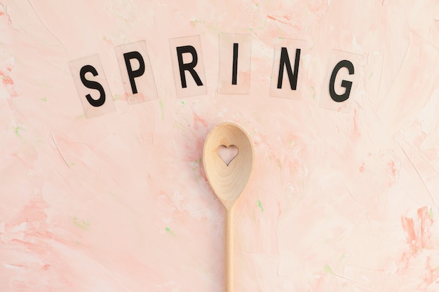 SPRING word and stirring spoon on a pink background