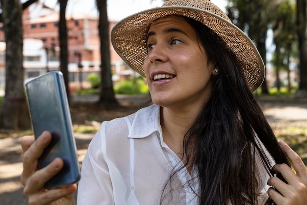 In spring young latin american woman 33 is in a park and uses
her cell phone to make a video call spring concept and
technology