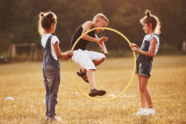 Foto springen door de cirkel fitness tool. kinderen hebben plezier in het veld.