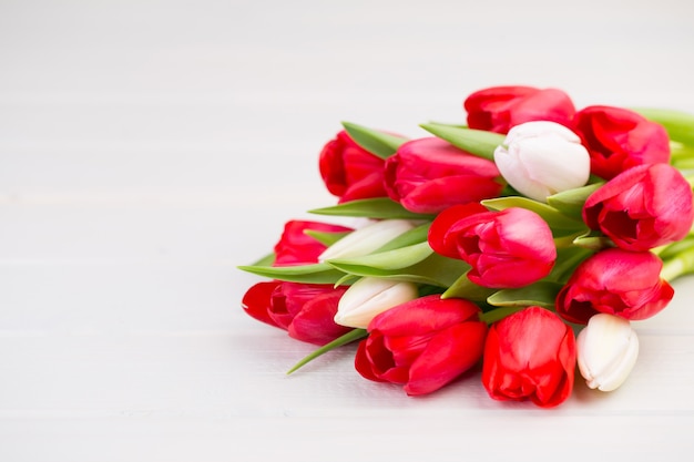 春の時間。白い木製の背景に赤いチューリップの花束。