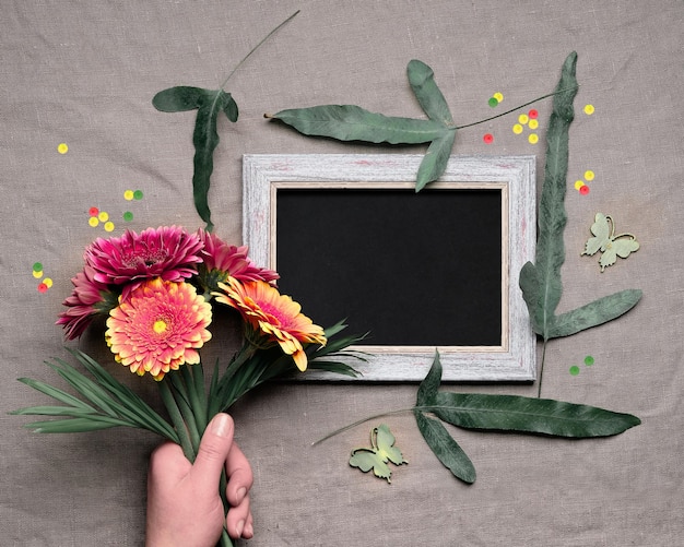 Foto sfondo primaverile tenere in mano un mazzo di vivaci fiori di gerbera foglie esotiche