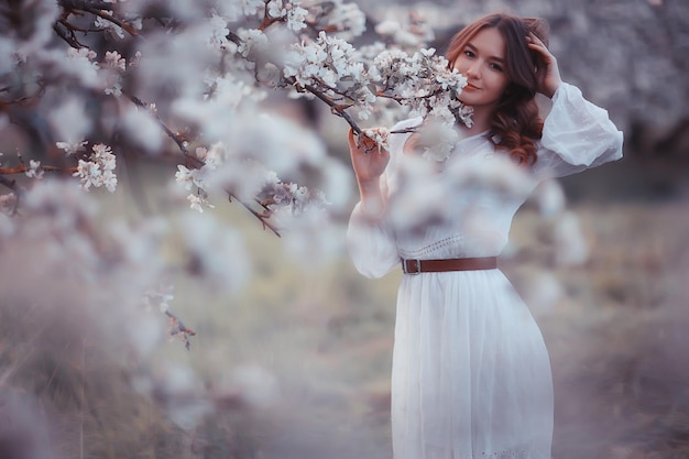 springtime fashion portrait of a young girl in a blooming cherry garden, tenderness of the morning