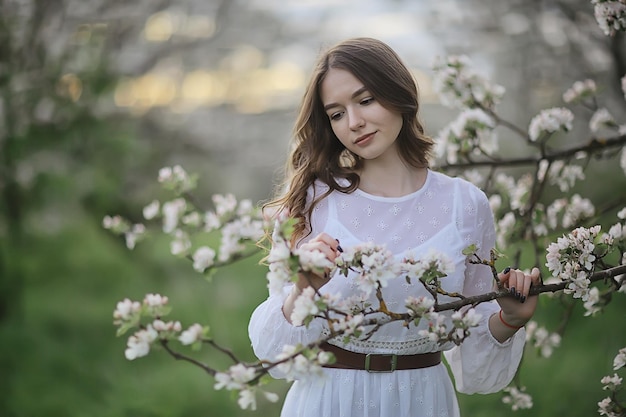 springtime fashion portrait of a young girl in a blooming cherry garden, tenderness of the morning