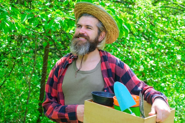 Springtime. Happy farmer in spring garden. Gardener with gardening tools.