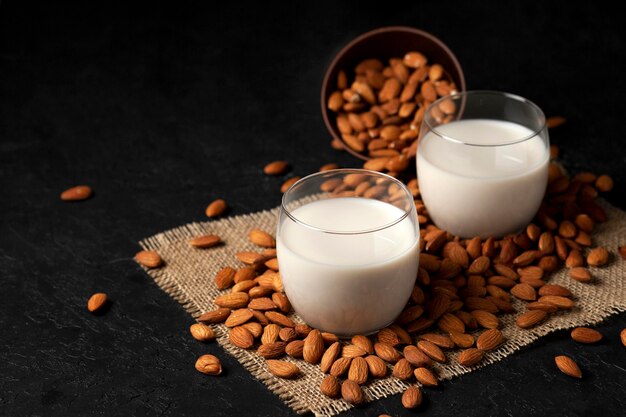 Sprinkled almonds with glasses of milk on a black background vegetarian milk