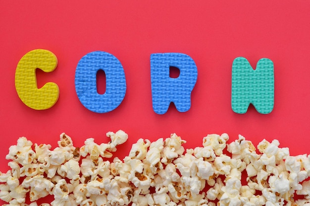 Sprinkled popcorn on a red background and the word corn