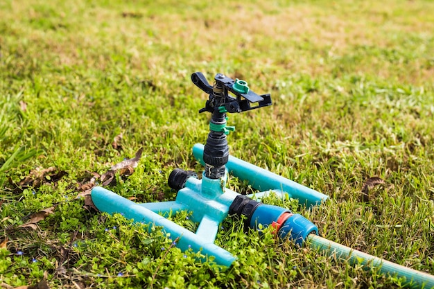 Sprinkler head for spraying water over green grass.