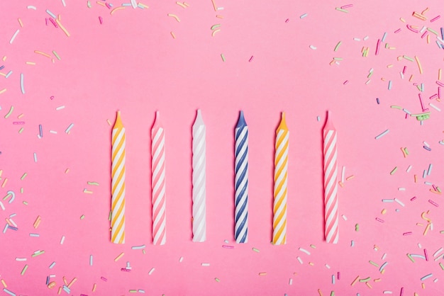 Photo sprinkles and row of candles on pink backdrop