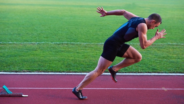 Foto sprinter die startblokken op de atletiekbaan verlaat. explosief begin.