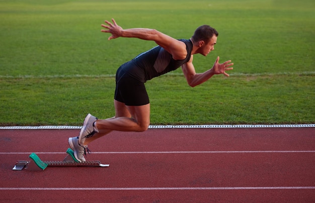 Sprinter leaving starting blocks on the running track. Explosive start.