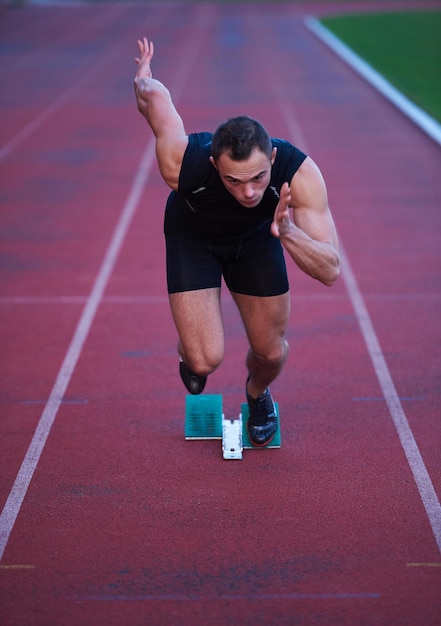 Sprinter leaving starting blocks on the running track. Explosive start.