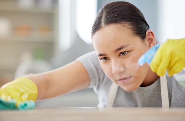 Sproeitafel en schoonmaken met een vrouwelijke huishoudster die desinfectiemiddel gebruikt om bacteriën in een huis te verwijderen Veiligheidsoppervlak en hygiëne met een jonge vrouwelijke schoonmaker die in de woonkamer van een huis werkt voor service