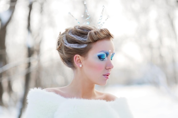 Sprookjesachtige cosplay van ijskoningin Portret van een vrouw in de jurk poserend in het besneeuwde bos