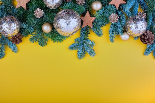 Spruce branch, cones and vintage toys decoration on christmas or new year on yellow background.