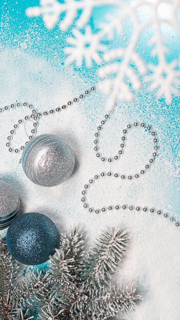 Spruce branch with Christmas toys on a snow-covered background