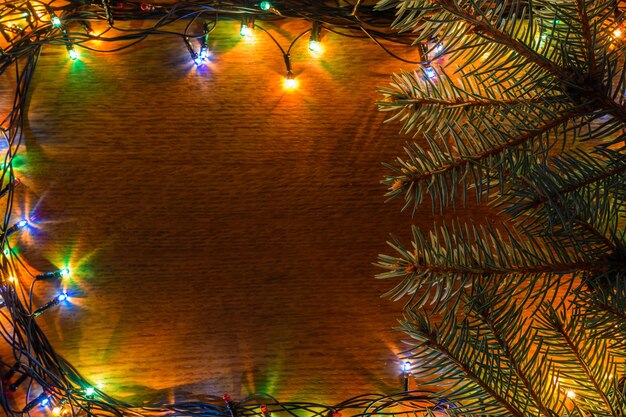 Spruce branches, garland and wooden background with a spear space.