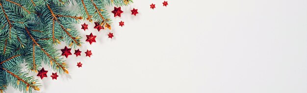 Spruce branches with red stars on white christmas and new year background