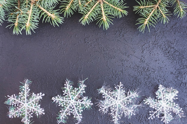 コンクリートの背景に雪片とトウヒの枝。ホリデーポストカード、招待状。新年とクリスマスの概念。コピースペース