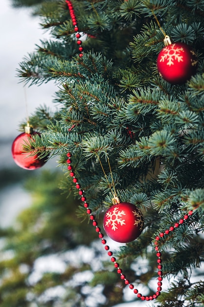 Photo spruce is decorated with red balls with a snowflake pattern and with beads stands at home