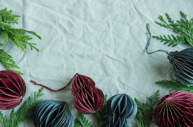 Spruce twigs and paper Christmas  decorations on the green linen crumpled textile background