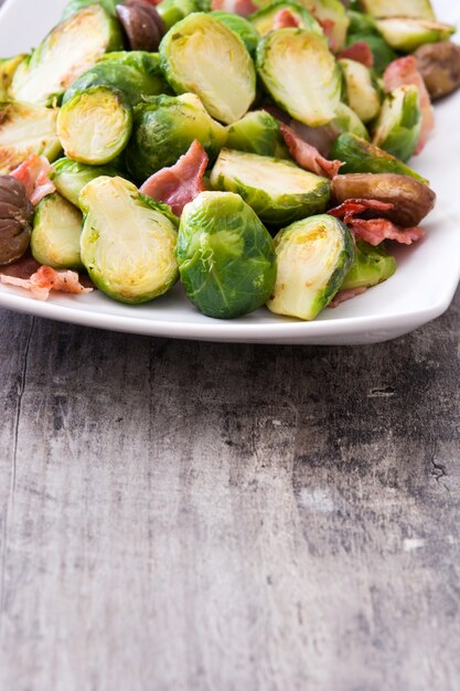 Spruitjes met kastanjes en bacon op houten lijst