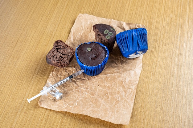 Spuit die insuline injecteert in beschimmelde chocolademuffin