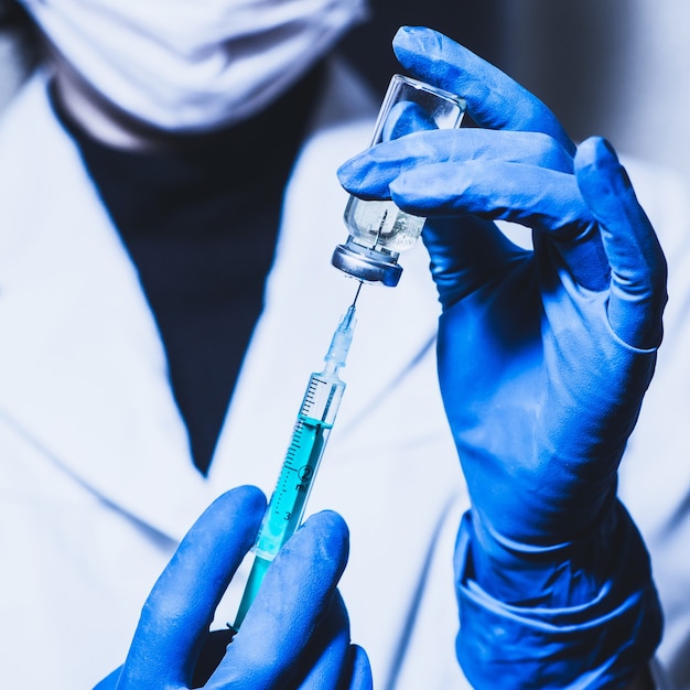 Spuit en hand close-up. Het concept van vaccinatie, het medicijn in de spuit vullen. Dokter achtergrond