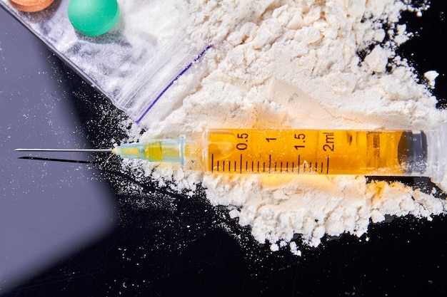 Spuit gevuld met dosis drugs op de stapel van wit poeder drugsverslaving concept