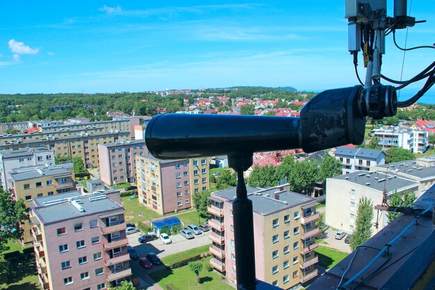 Photo spyglass standing at window with city panorama cityscape with a lot of multystored houses window with spyglass at city panorama in polish town wladislawowo