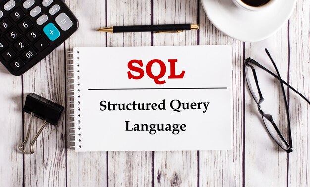 SQL Structured Query Language wordt geschreven in een wit notitieblok naast een rekenmachine