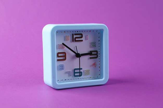 Square alarm clock on purple background