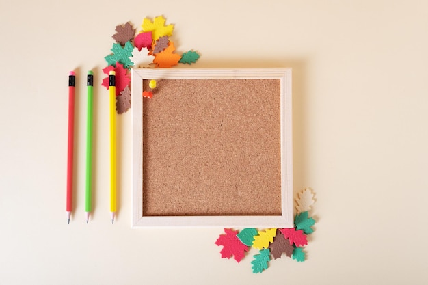 Square cork board for notes with pencils decorated with autumn leaves of different colors