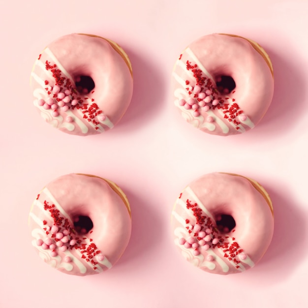 写真 パステル調の背景にピンクのアイシングと甘いドーナツの正方形の作物。ピンクの質感のおいしいドーナツ