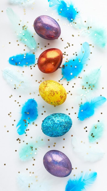 Photo square of easter eggs on a white background scattered blue feathers banner for text