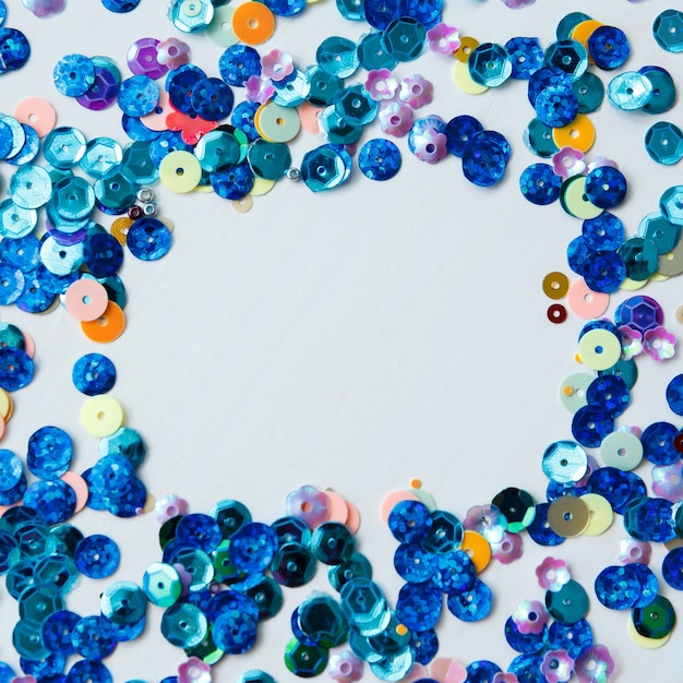 Square frame on wooden background from colored and blue sequins