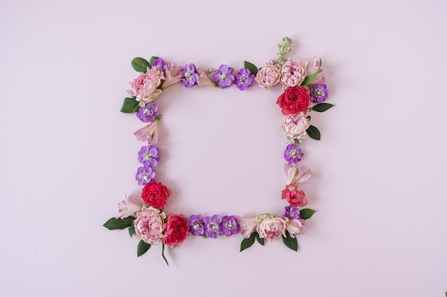 Square frame wreath with blank mockup copy space made of pink\
rose flowers on pink background flat lay top view minimal floral\
composition