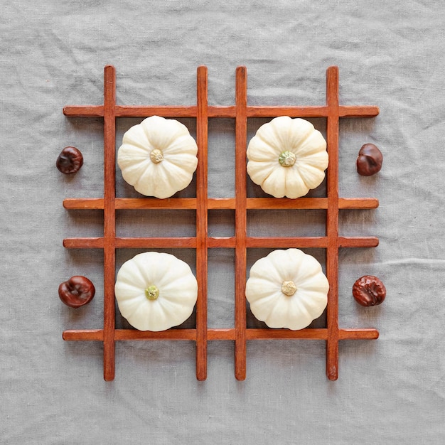 Square geometric Autumn background with natural pumpkins, chestnuts . Flat lay, top view on grey linen textile. Natural Fall background in dark red, brown and grey.